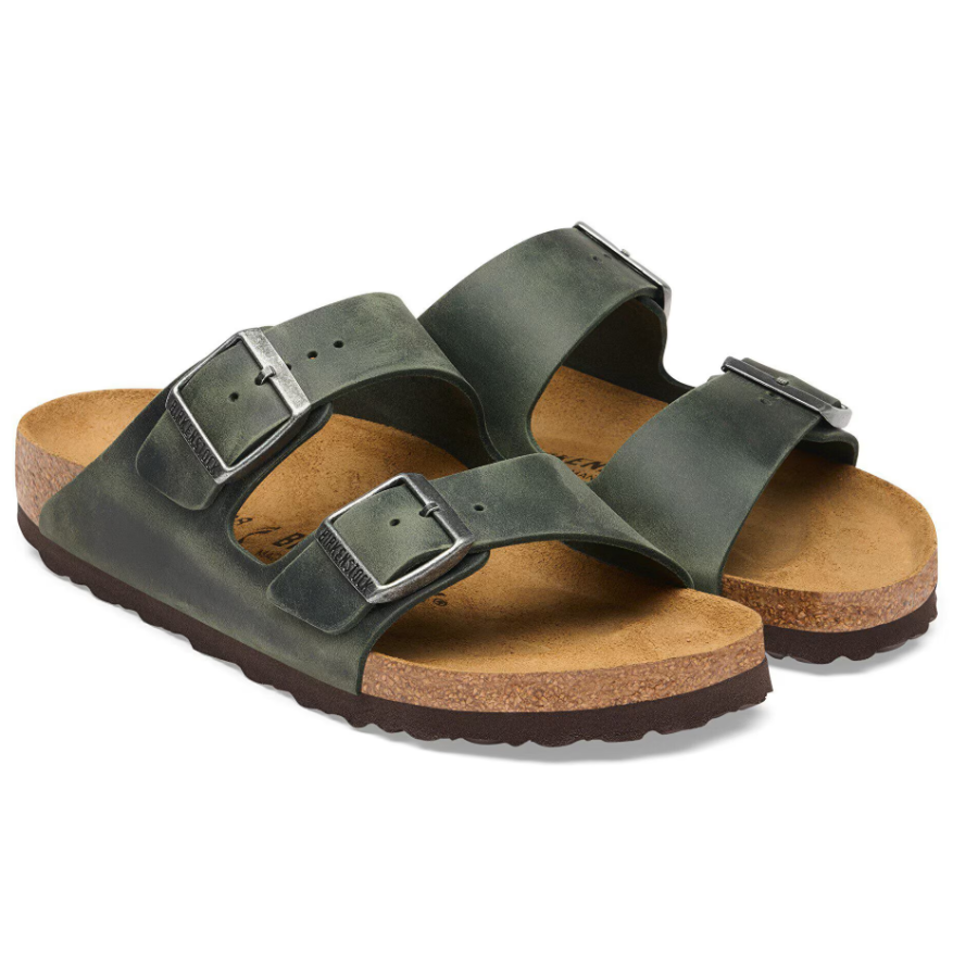 A pair of dark olive green double-strap slide sandals with adjustable metal buckles, cork midsoles, and dark brown outsoles, shown on a plain white background.