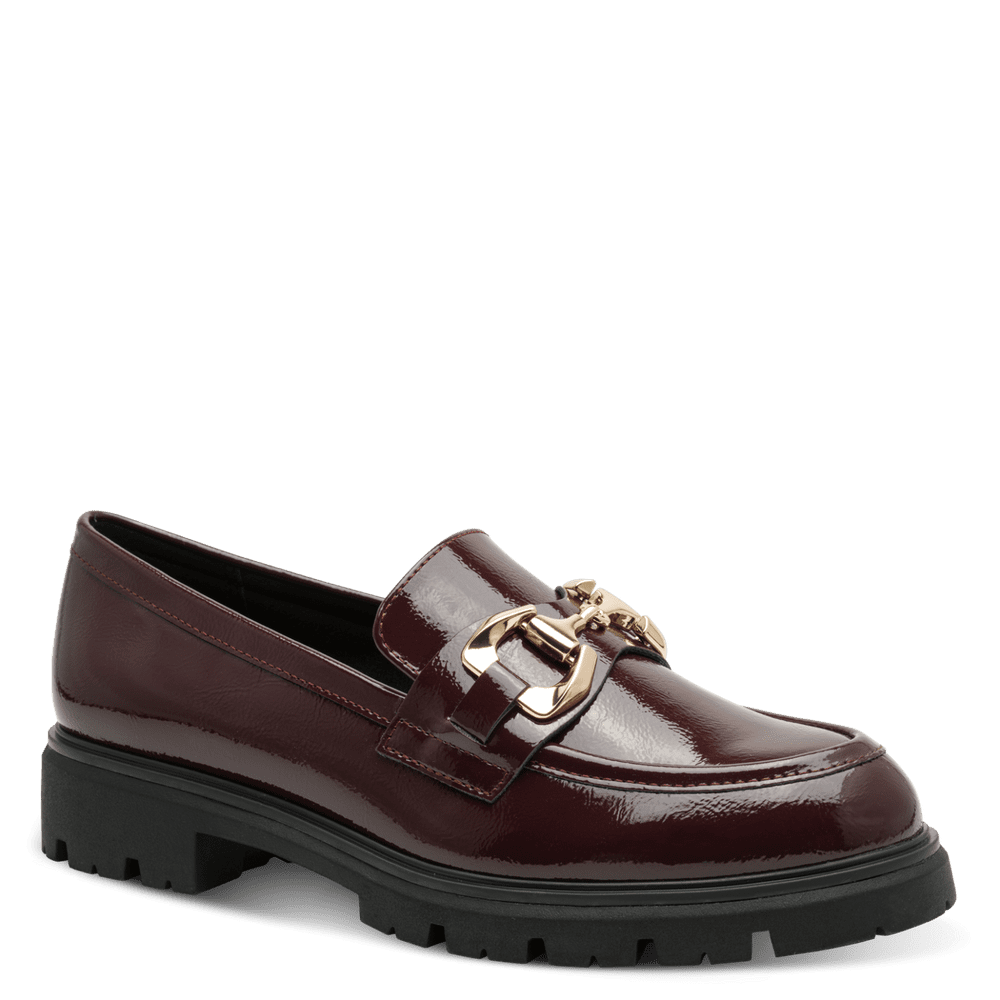A single burgundy patent leather loafer with a chunky black lug sole and a gold-tone horsebit detail on the strap, shown against a solid green background.